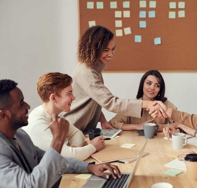 Diverse team collaborating in a meeting, showcasing teamwork and cooperation in a modern workplace.